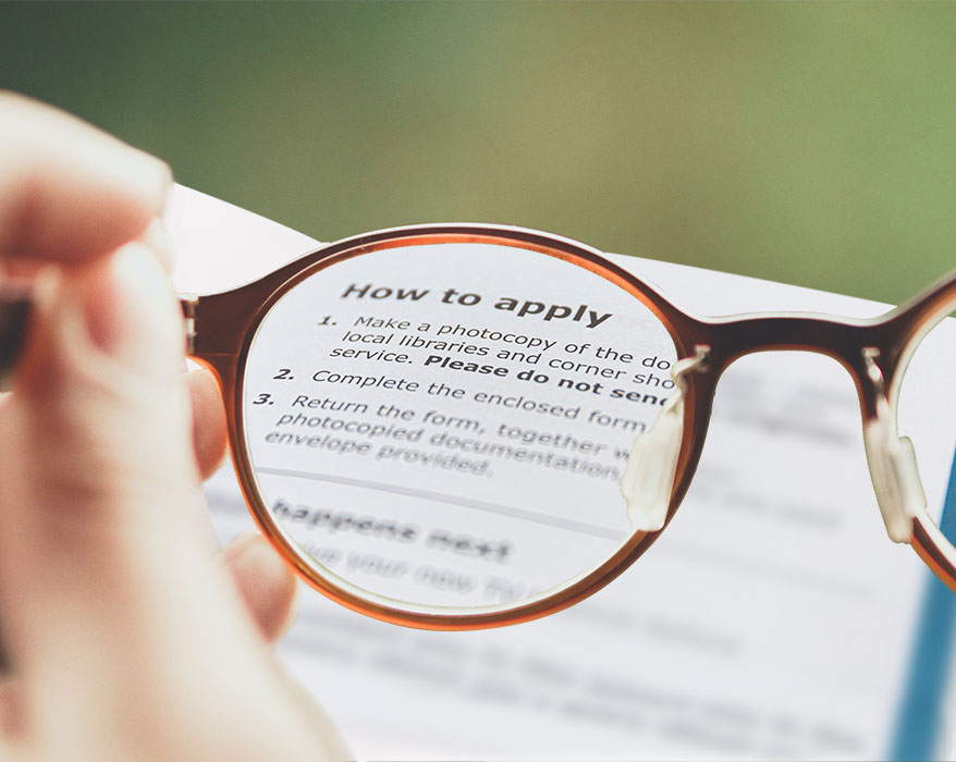 This is an image showing a person holding glasses to bring text on a page into focus. It is the porfolio image representing our contribution to the design of a legal aid portal.